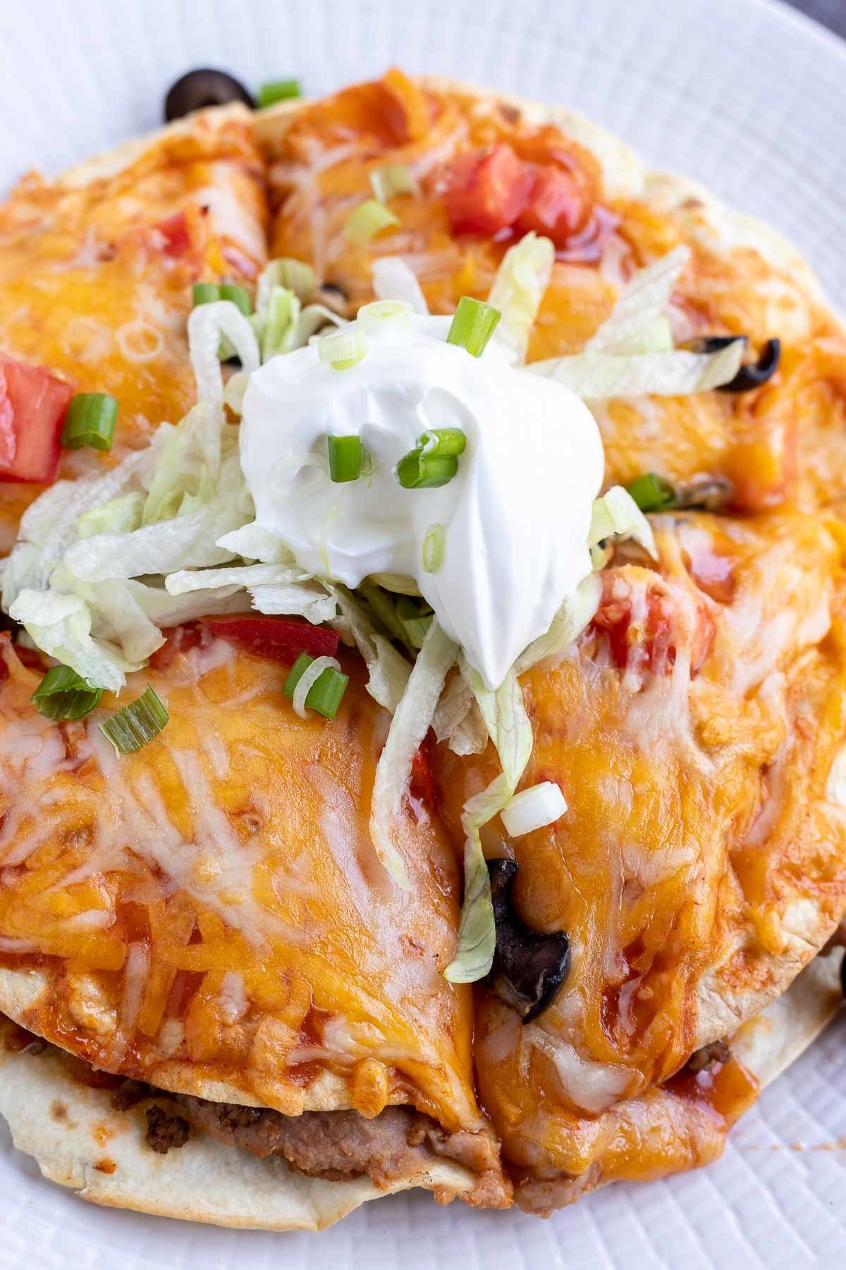 A Mexican pizza topped with refried beans, cheese, and sour cream.