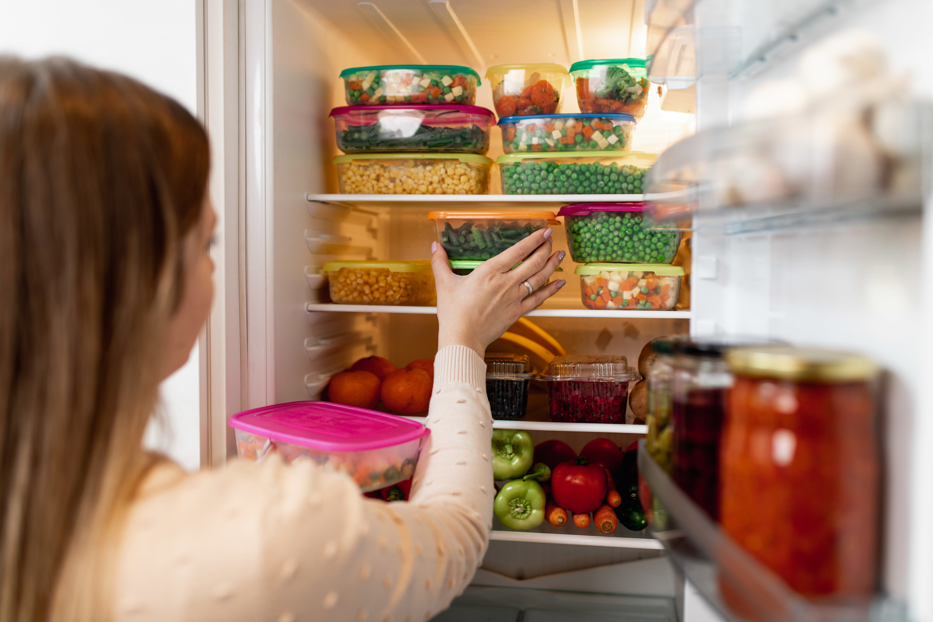 Close-up shot of woman putting a food container into the fridge.